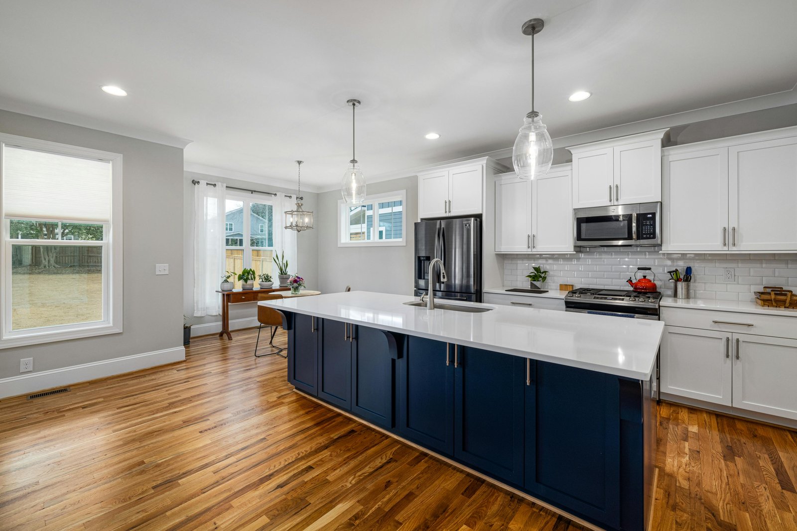 Modern custom home kitchen with white cabinets, navy island, and clean recessed lighting in the ceiling